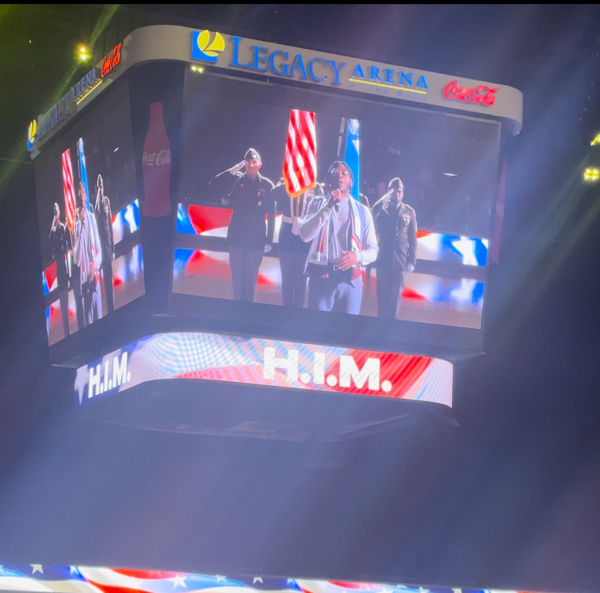 People on a large screen at Legacy Arena, with American flags and a red, white, and blue theme, celebrating an event.