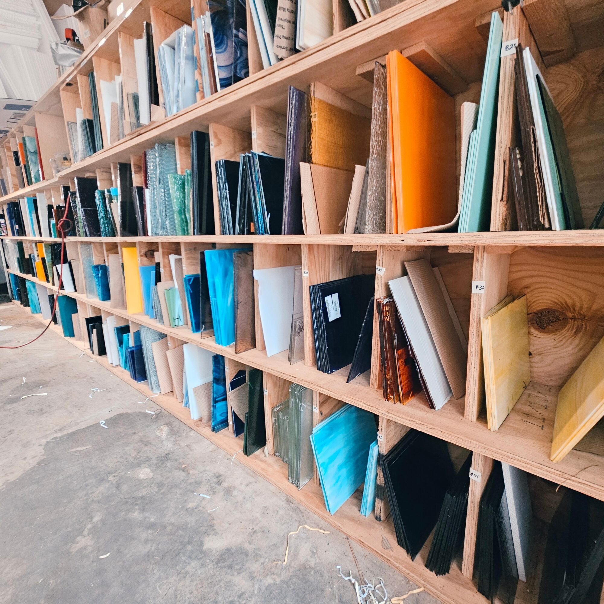 Bookshelves filled with books and binders in a library or bookstore setting, viewed from an angle.
