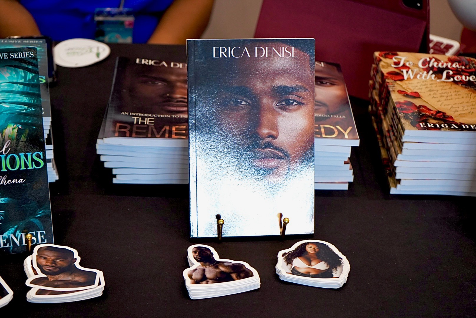 Book titled 'Erica Densie' with a close-up of a person's face on display, surrounded by other books and paper cutouts.
