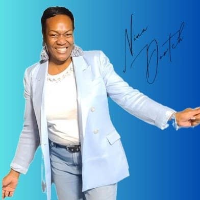 Smiling woman in light blue suit with signature on blue background, arms extended outward.
