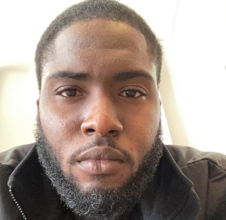 Close-up of a man with short hair and a beard, looking directly at the camera, neutral expression.