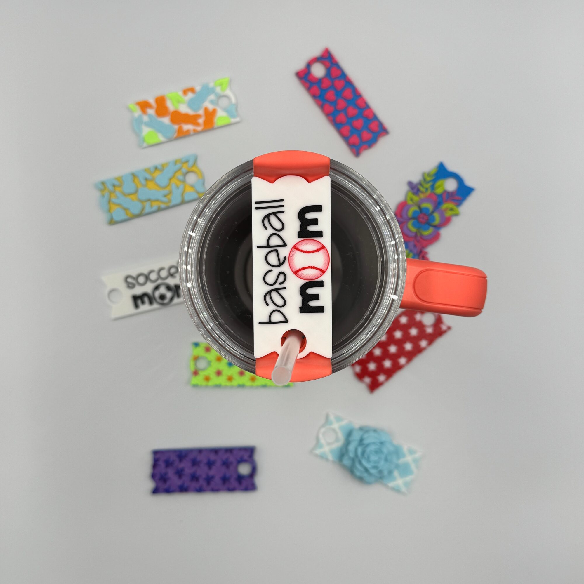 A mug with a baseball design, surrounded by colorful patterned paper strips on a white background.