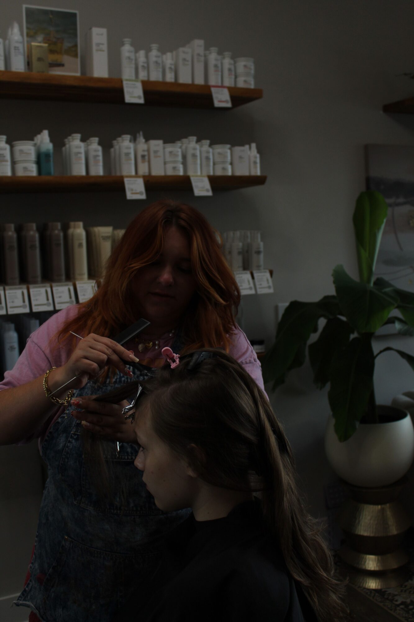 Two women with long hair looking at shelves with labeled boxes in a room, one with red hair and the other with brown hair.