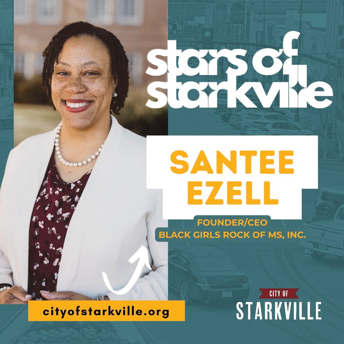 Portrait of Santee Ezell smiling, wearing a white blazer and pearl necklace, with cityscape background.