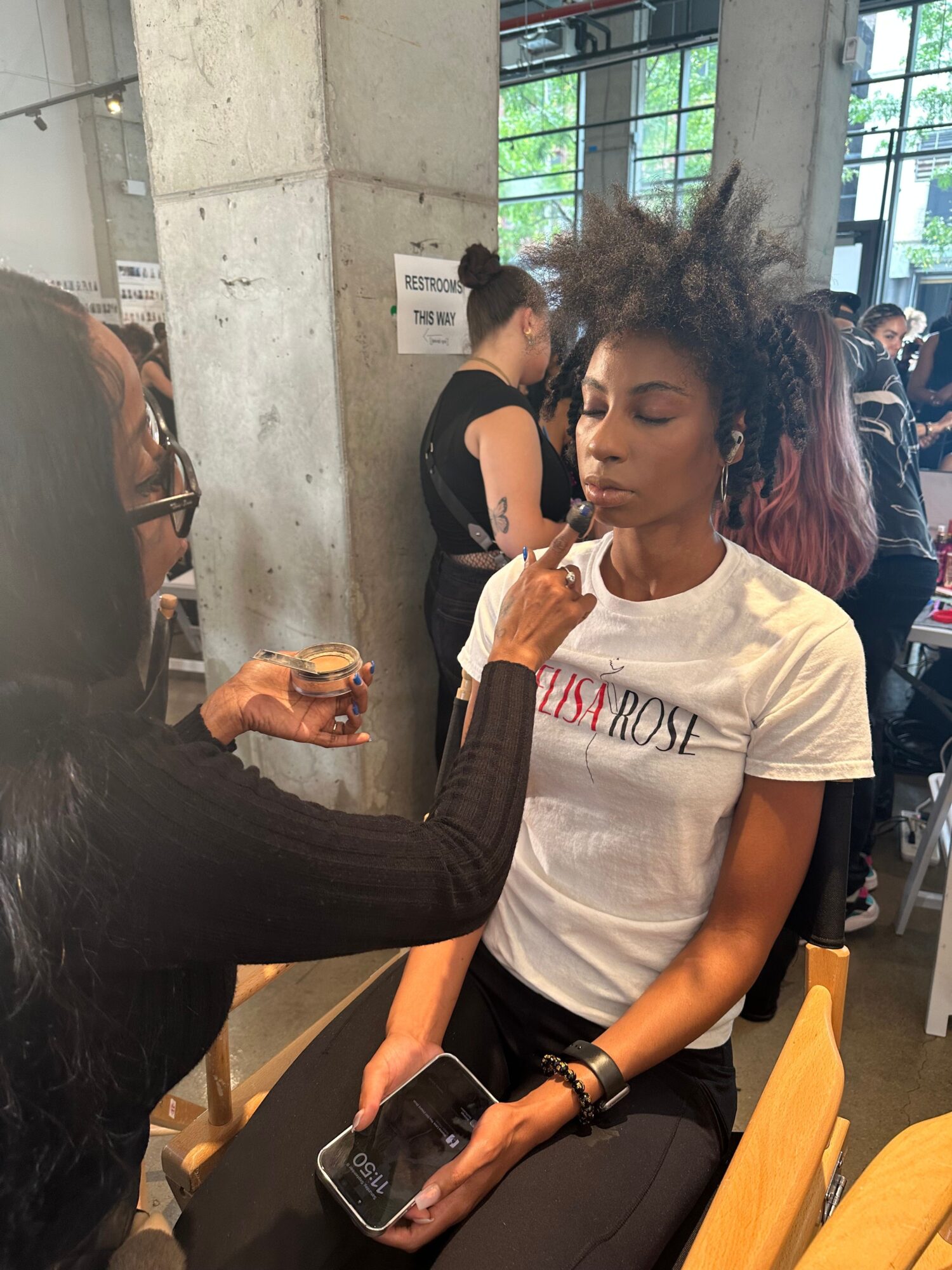 Two women sitting at a table in a cafe, one holding a cupcake and the other with a phone, in a modern indoor setting.