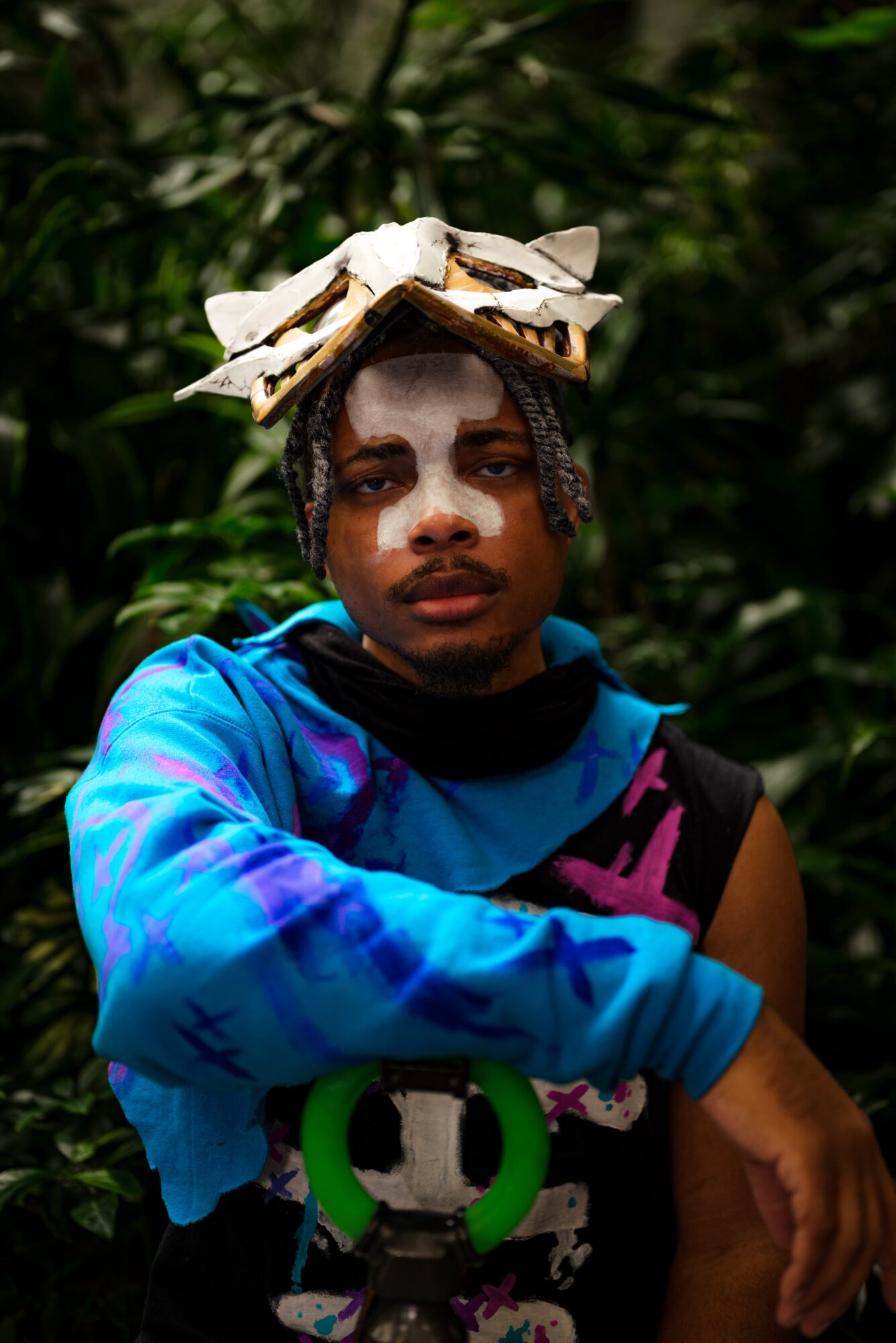 Person with a large butterfly on their head, wearing a blue and black shirt, in a green outdoor setting.