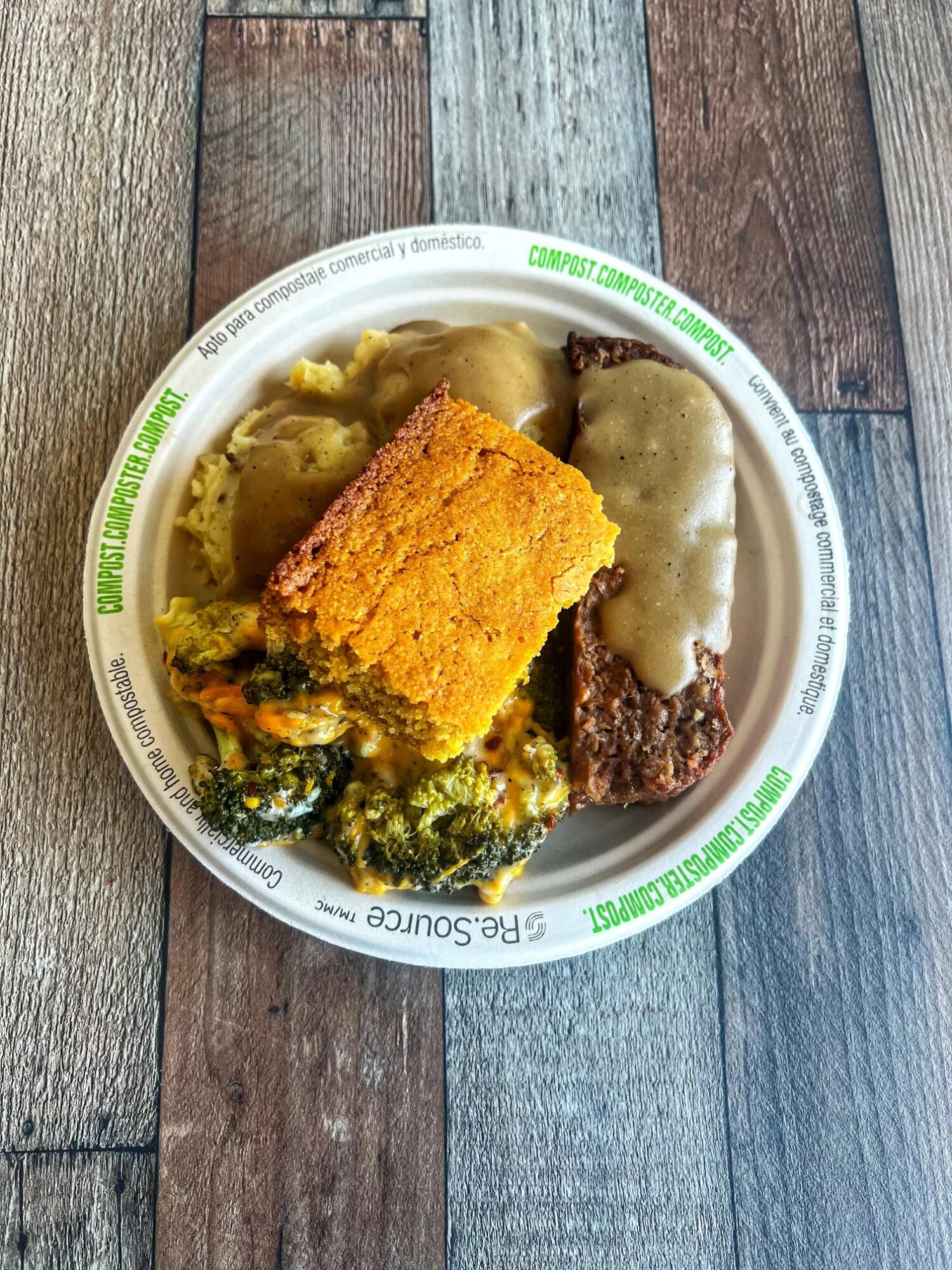 Plate with fried food, vegetables, and sauce on a wooden surface, viewed from above.