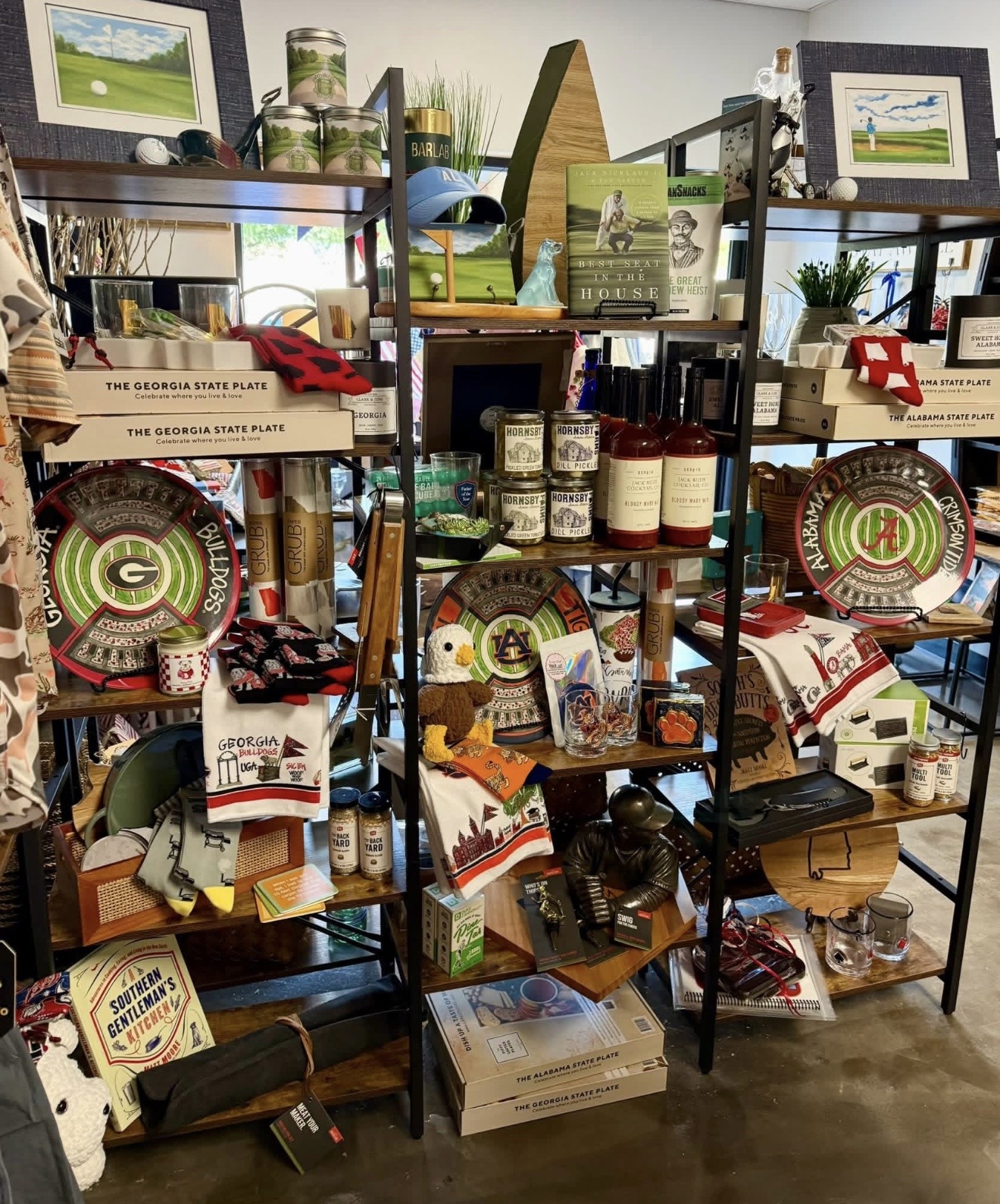 Shelves filled with various products, framed pictures, and decorative items in a store setting.