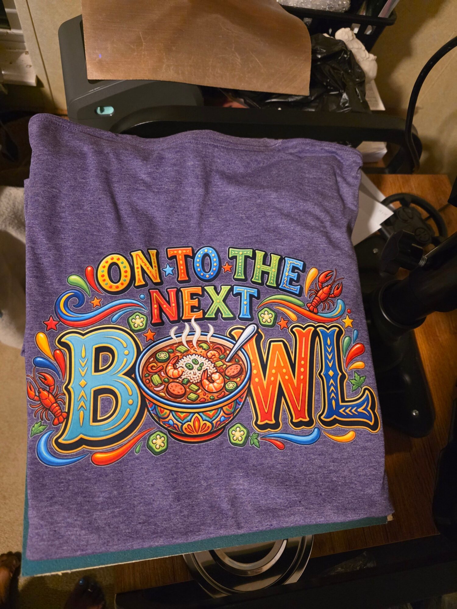 Purple towel with colorful text and design, reading 'ON TO THE NEXT! DOW!'