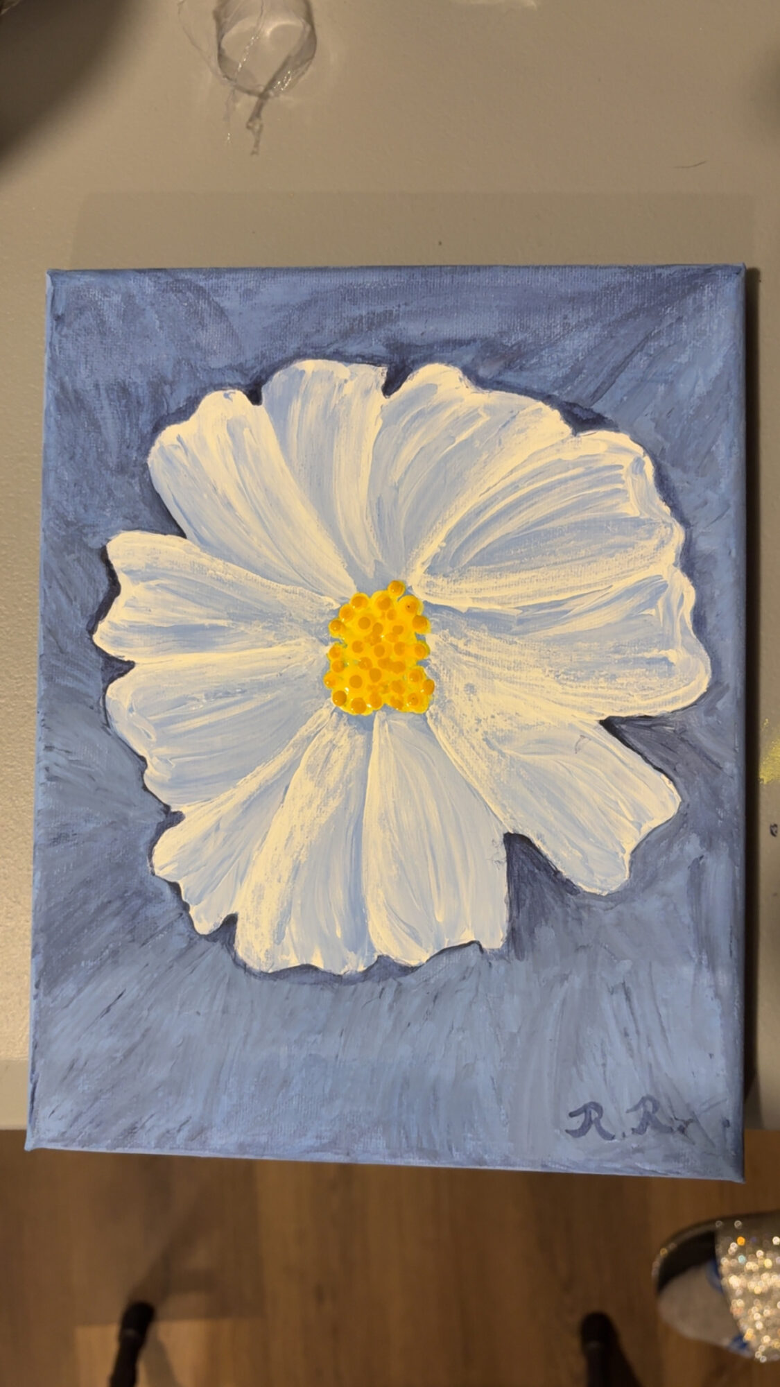 Painting of a white flower with a yellow center on a blue background.