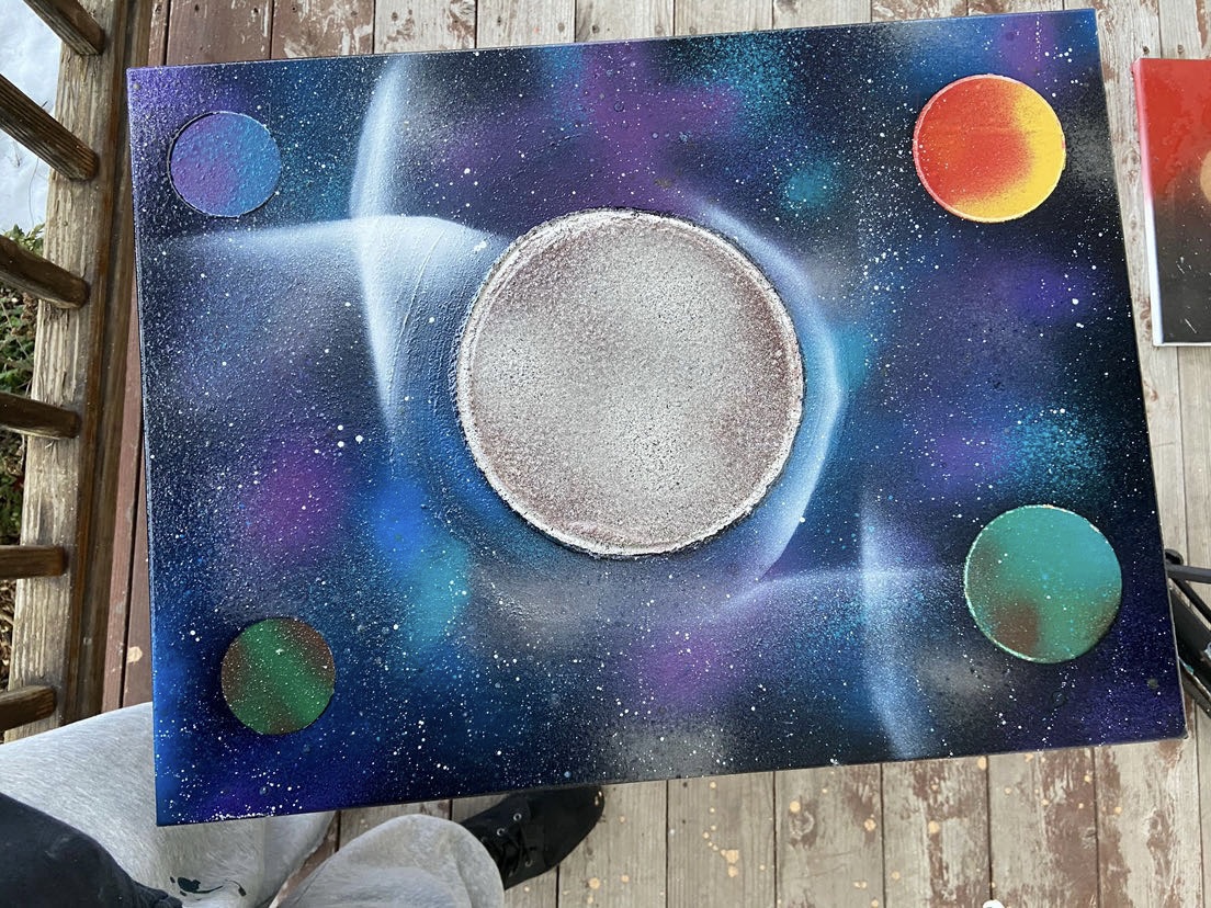 A space-themed painting with planets and stars, featuring a large central circle and colorful cosmic background.