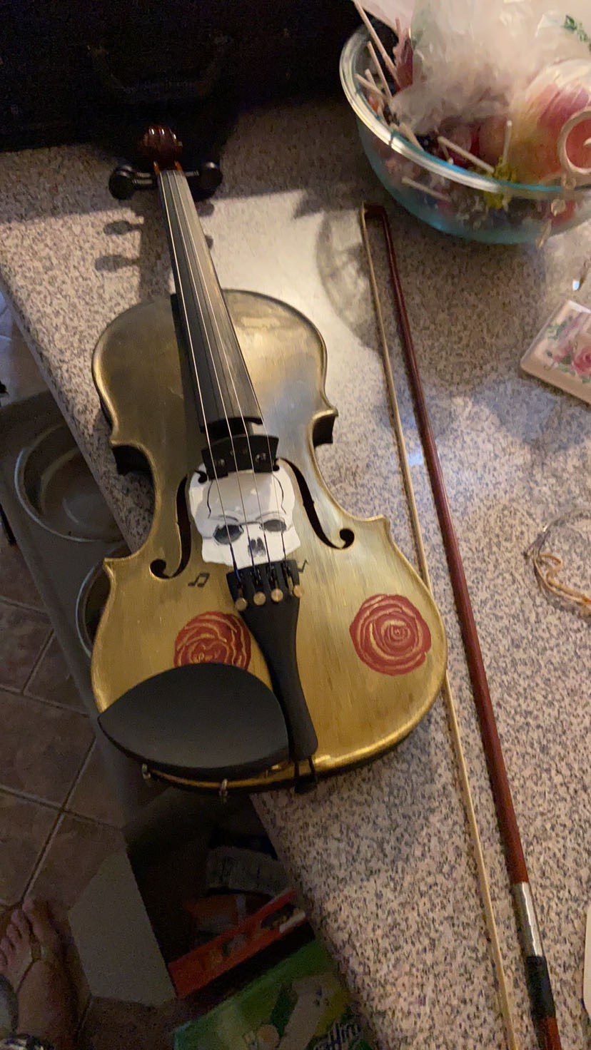 Violin with bow resting on a table, with a bowl of candies nearby.