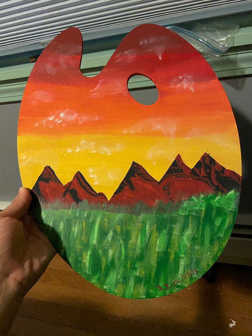 Painted landscape with mountains, green grass, and a sunset sky in red, orange, and yellow hues.