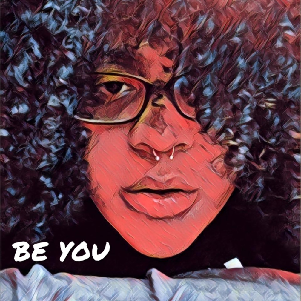 Close-up of a person with curly hair, glasses, and a septum piercing, with the words 'BE YOU' in the corner.