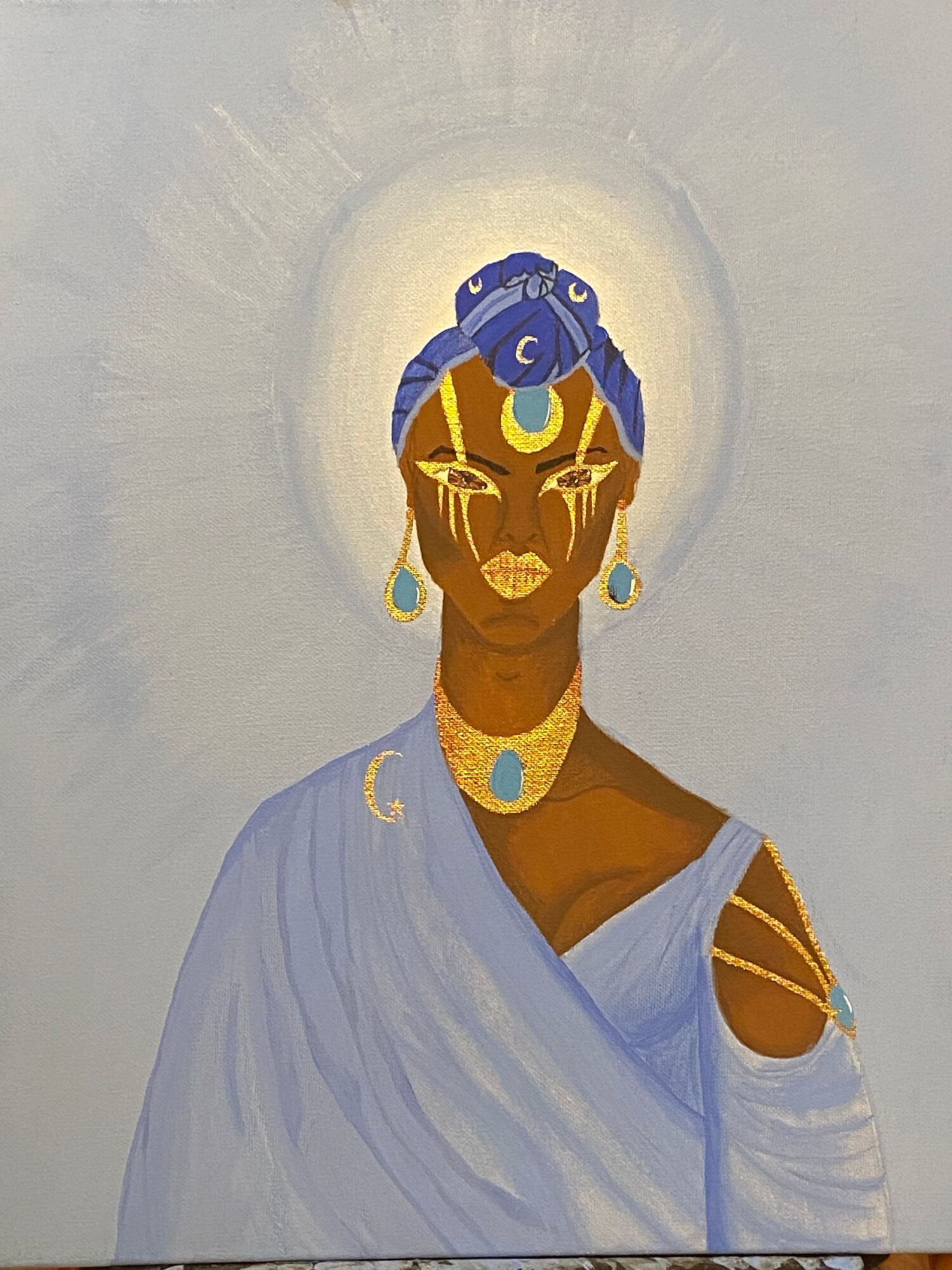 Portrait of a woman with dark skin, adorned with gold jewelry and a blue headwrap, wearing a light blue garment.