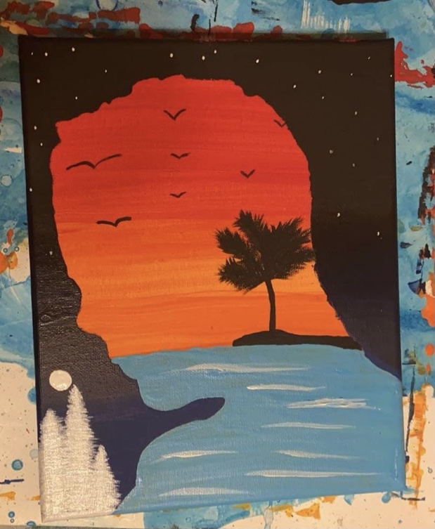 Sunset over a beach with a tree, birds flying, and water, with cliffs on the sides.
