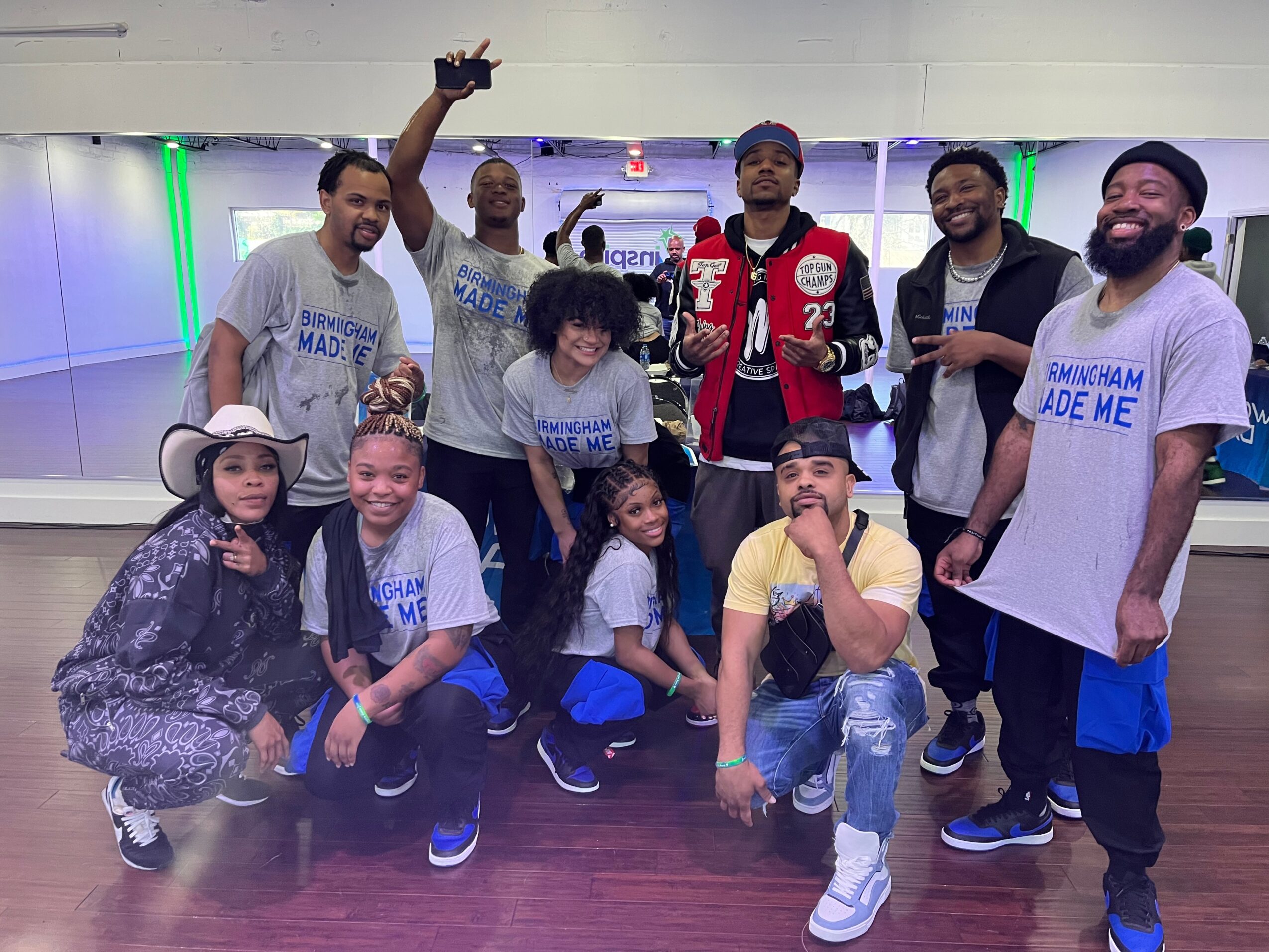 Group of ten people posing in a bowling alley, some making gestures, smiling, and wearing casual clothing.