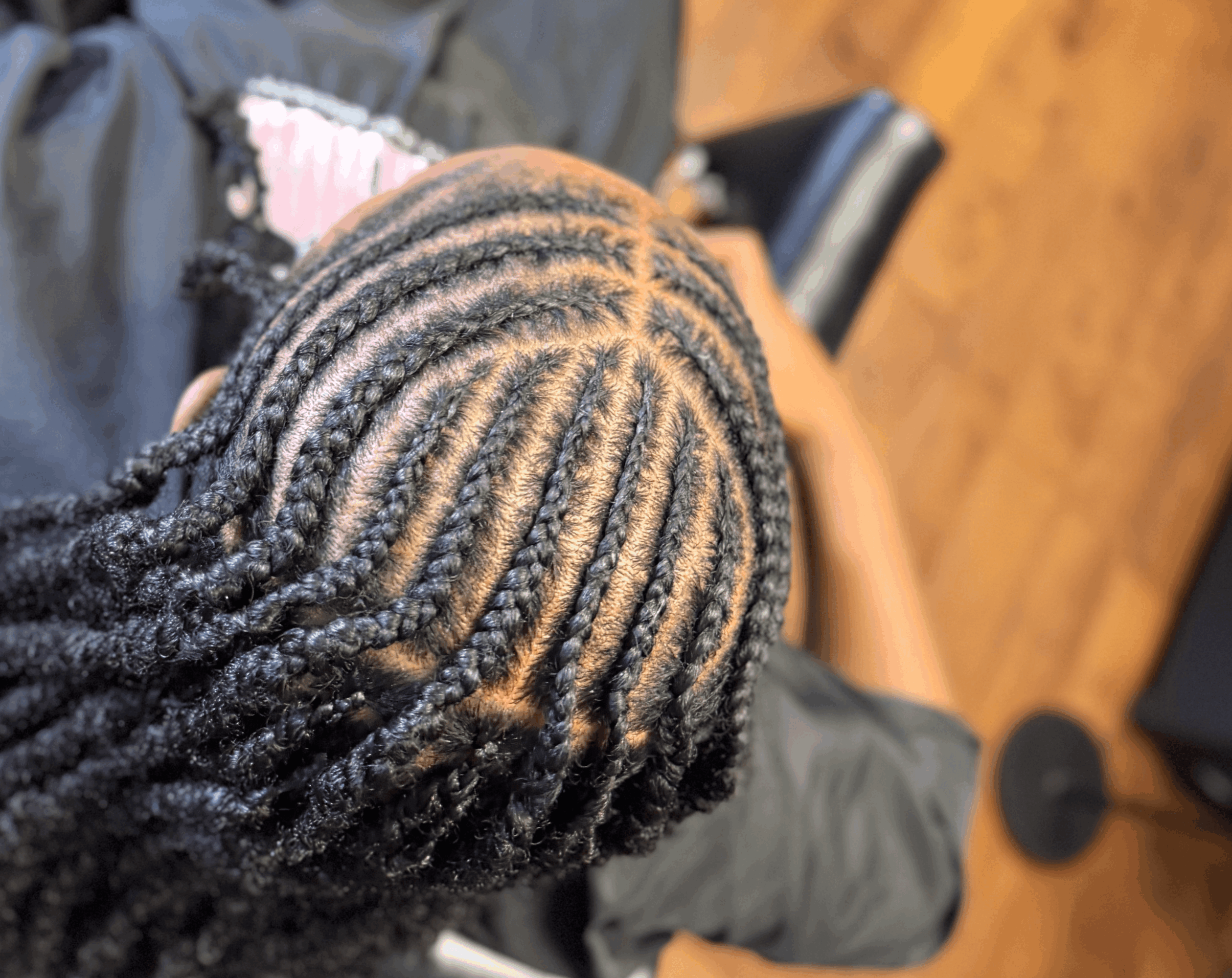 Top view of a person's head with neatly styled dreadlocks, showing a circular pattern, indoors with wooden flooring.