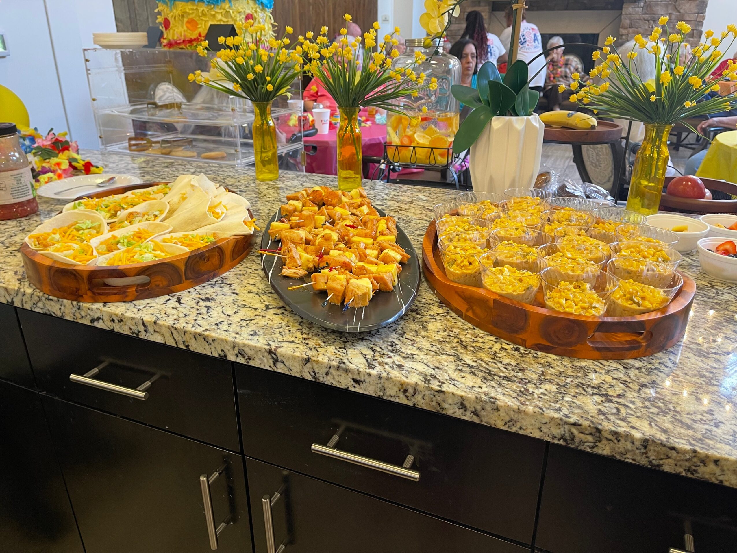 Assorted desserts on a granite countertop with flower arrangements in the background.