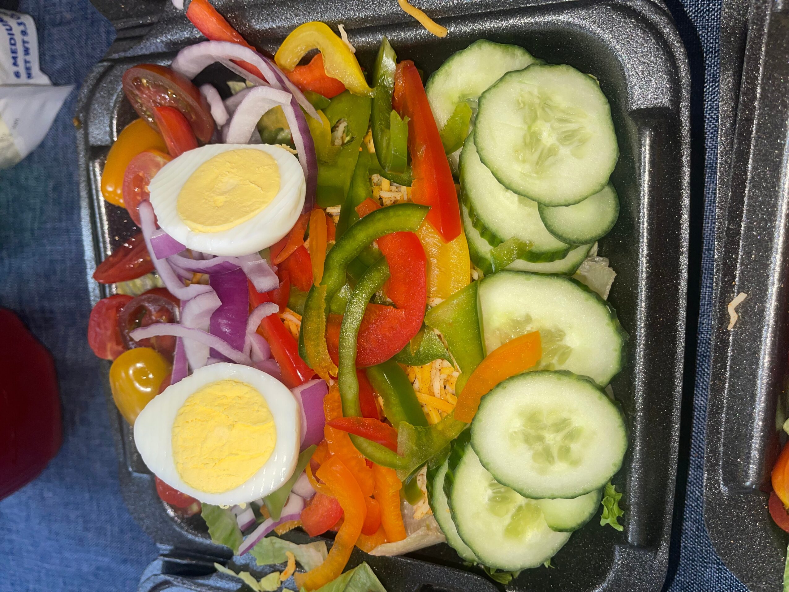 Sliced cucumbers, boiled eggs, and mixed vegetables including red, yellow, and green peppers, and onions.